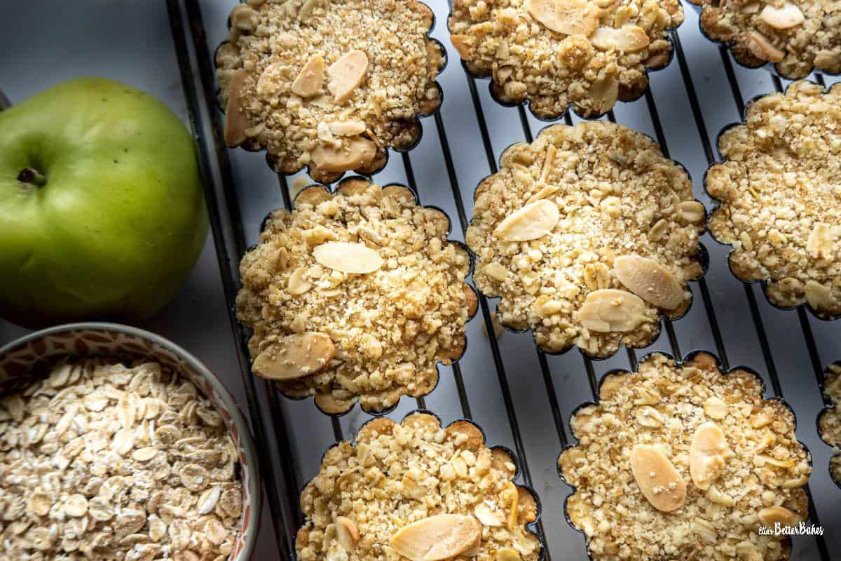 apple crumble tartlets on cooling rack next to ingredient