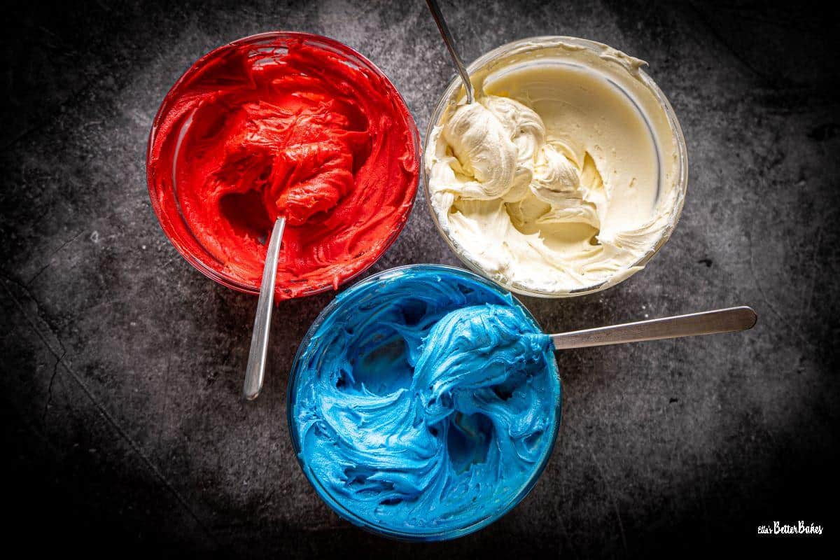 red, white and blue buttercream in 3 bowls
