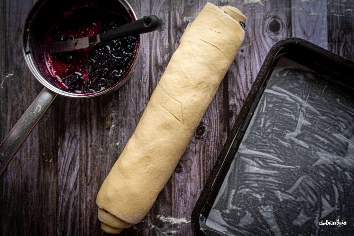 blueberry and cinnamon dough rolled up ready to cut