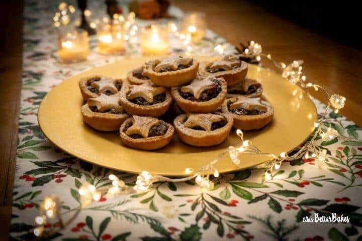 mince pies on a plate and table rummer next to lights