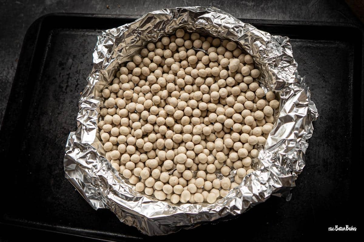 baking beans tipped onto pastry case ready to bake