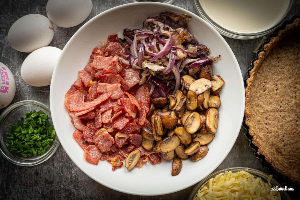 fried bacon, onions with garlic and mushrooms cooked and in a dish