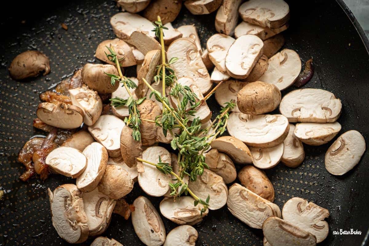 thyme and mushrooms added to a pan